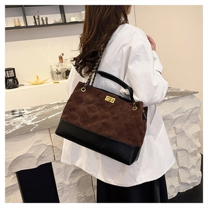 Detail of brown suede and black leather patchwork bag with classic diamond quilting