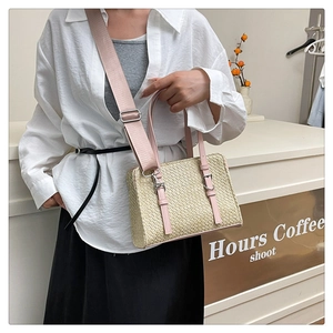 Detail of woven beige straw bag with pink leather trim and wide nylon crossbody strap