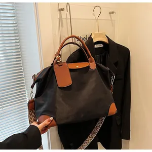 Detail of black nylon tote bag featuring brown leather handles and a geometric shoulder strap