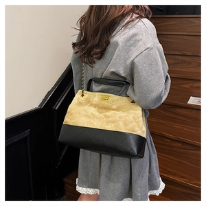 Detail of suede tote bag with diamond quilting, gold chain strap and turn-lock closure
