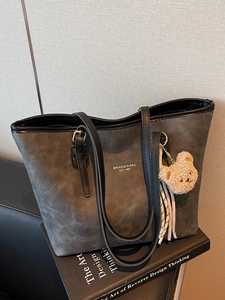 Grey matte tote bag with black trim and cute plush bear charm for daily commuting