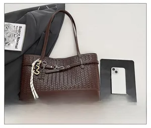 Detail view of large woven tote bag in dark brown with decorative charms and metal ring