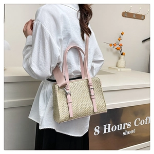 Detail of bohemian straw handbag featuring pink leather trim and adjustable woven shoulder strap