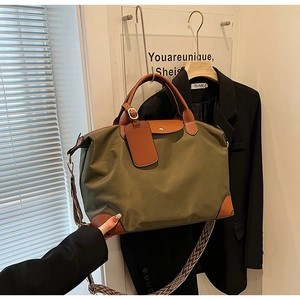 Detail of army green nylon tote featuring brown leather handles and woven shoulder strap