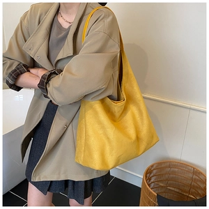 Detailed view of large yellow frosted suede tote bag worn on shoulder by model