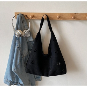 Detail of laser-cut floral pattern on black suede tote bag with a minimalist design