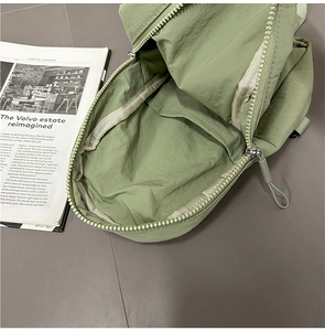 Detail of avocado green nylon bag interior with zippered compartment and smooth lining
