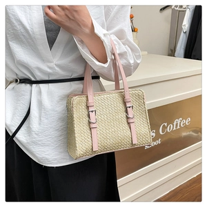 Detailed shot of straw tote with pink leather straps and silver metal buckle accents