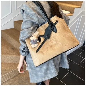 Detail of khaki suede tote bag with black leather straps and cute plush dog charm