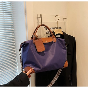 Detail of purple nylon tote bag featuring brown leather handles and geometric woven strap