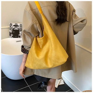 Detail of yellow suede hobo bag shown in a minimalist setting for daily commute