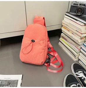 Detail of coral pink nylon chest bag with drawstring pocket and casual student props