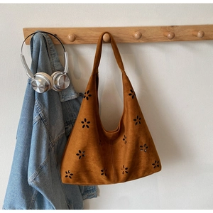 Detail of laser-cut flower patterns on brown faux suede shoulder bag with stitching