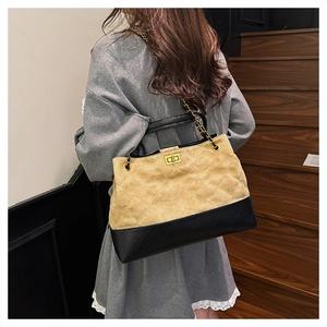 Detail of vintage suede tote bag showing bicolor contrast and chain strap on a model