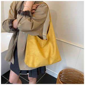 Detailed view of yellow matte suede tote bag worn on shoulder for stylish daily commute