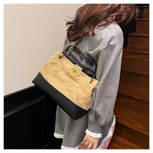 Detail of vintage suede and leather patchwork tote featuring golden metal twist lock and chain