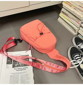 Detail of coral orange nylon sling bag with adjustable elastic drawstring texture