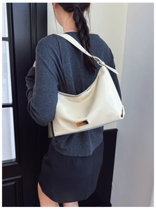 Close-up of cream crescent underarm bag with silver zipper and metallic logo plate
