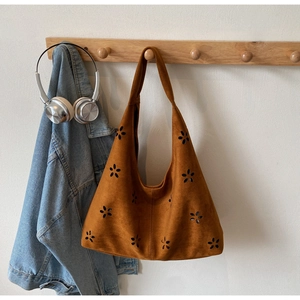 Close-up of caramel tote bag featuring laser-cut floral patterns and soft faux suede texture