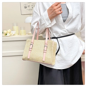 Detail of woven straw handbag texture featuring pink leather straps and silver buckles
