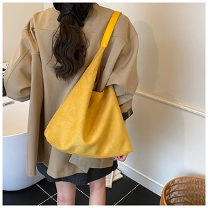 Close-up of a large yellow suede hobo bag worn over the shoulder for a stylish commuter look