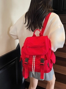 Minimalist red nylon backpack for women featuring flap closure and buckle straps