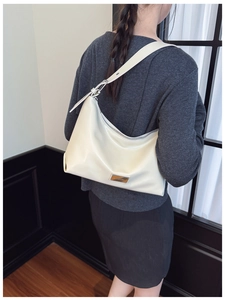 Detail view of cream white underarm bag with silver zipper and adjustable strap