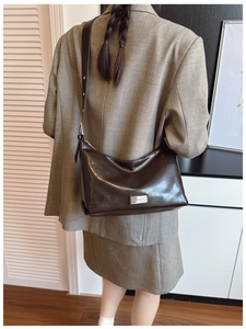 Detail of dark brown leather underarm bag with adjustable strap and silver buckle