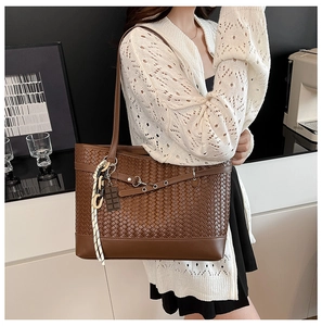 Close-up of brown woven tote bag with chain strap and leather base in modern interior