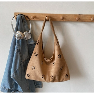 Close-up of brown suede tote bag featuring intricate floral laser-cut hollow patterns