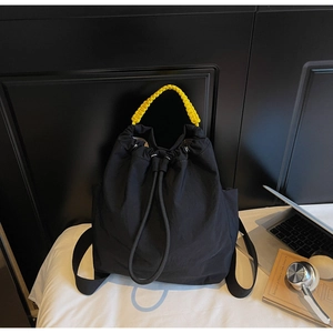 Dettaglio borsa a secchiello in nylon nero con manico intrecciato giallo e coulisse