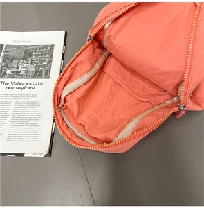 Detailed interior of coral nylon backpack showing spacious main compartment and inner pocket