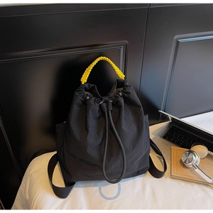 Dettaglio borsa a coulisse in nylon nero con manico giallo intrecciato e accessori moda