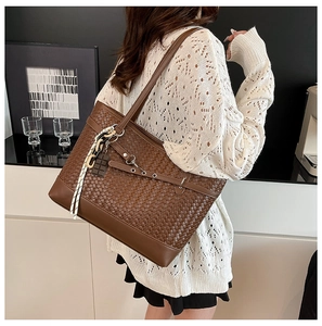 Close-up of brown woven tote bag with leather piping, chain and silk scarf detail