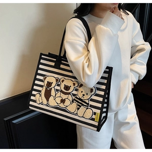 Détail du sac cabas en toile rayée avec trois oursons en peluche 3D et sangles noires