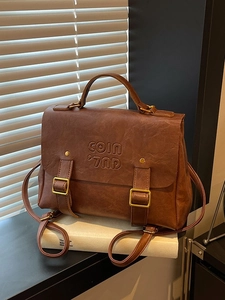 Vintage brown leather backpack with metal buckles and top handle in natural sunlight