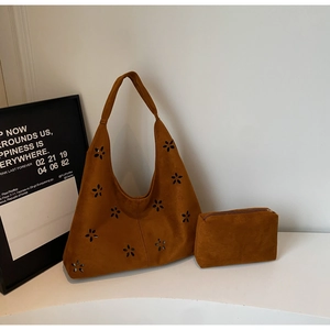 Detail of caramel suede tote bag with laser-cut floral patterns and matching inner pouch