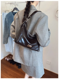 Detail of dark brown leather hobo bag featuring silver zipper and adjustable shoulder strap