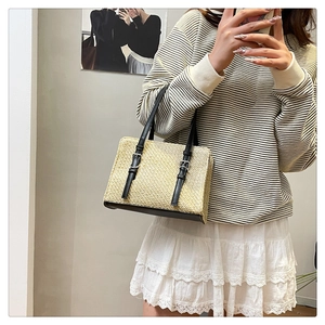 Detail of rectangular straw tote bag with black leather base and silver metal buckle