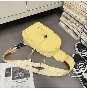 Detailed view of light yellow nylon chest bag featuring functional drawstring pocket design