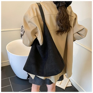 Model wearing a large black frosted leather tote bag for professional minimalist office style