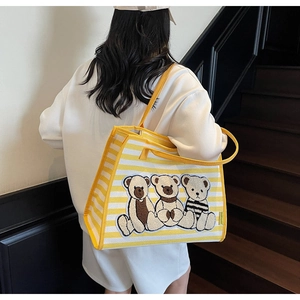 Détail du sac cabas en toile rayée avec broderie ours en peluche sur fond jaune