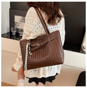 Detailed view of dark brown woven tote bag with adjustable strap and braided accessory