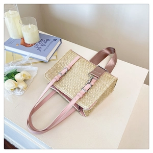 Detail view of woven straw beach bag with pink leather trim and textured fabric handle