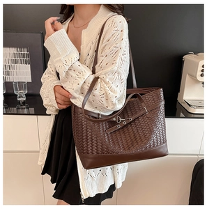 Close-up of dark brown woven tote bag featuring silver buckle detail on high-quality leather