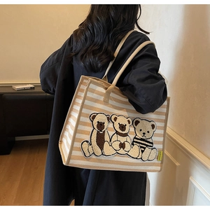 Vue détaillée du grand sac cabas en toile rayée avec broderie ours porté par un modèle