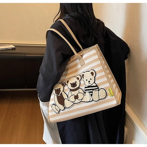Gros plan du sac cabas rayé en toile avec trois patchs brodés de peluches oursons