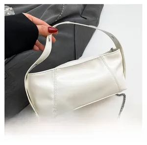 Macro detail of white leather cylinder bag with silver chain strap and wide handle