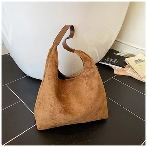 Close-up of brown suede hobo bag texture and wide shoulder strap detail on the bag