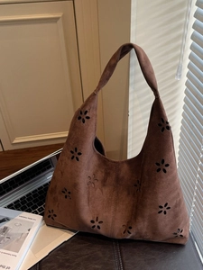 Brown suede tote bag with laser-cut floral patterns shown in warm natural sunlight